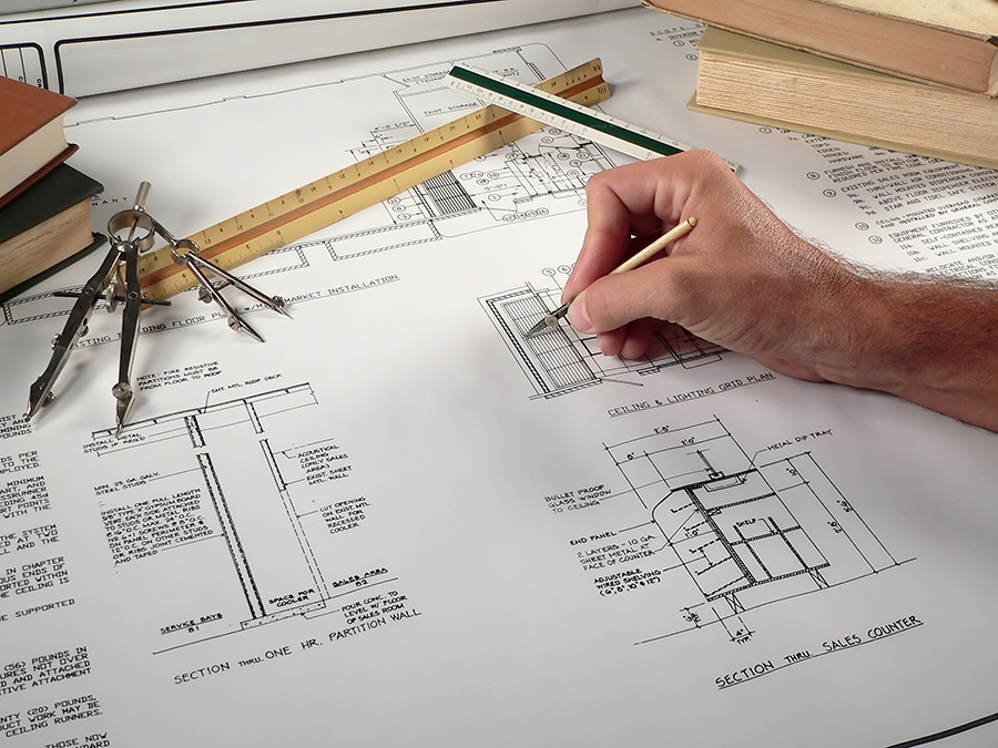 A person drawing on a building plan representing the projects of commercial construction company Via Meridiana Contractors LLC in Westmont, IL